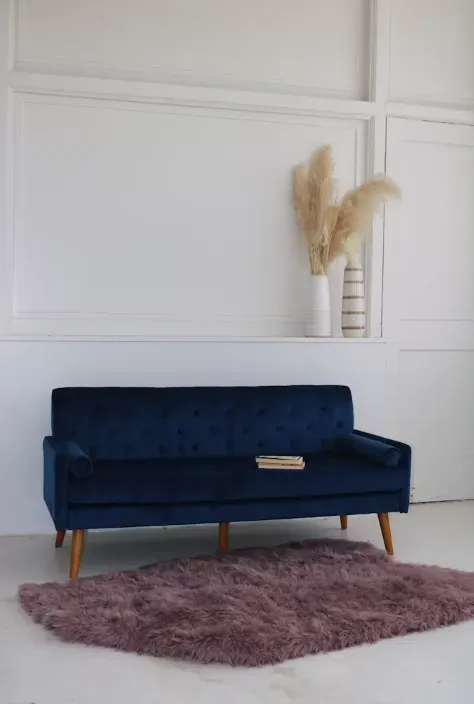 Divano in velluto blu con tappeto e vaso decorativo